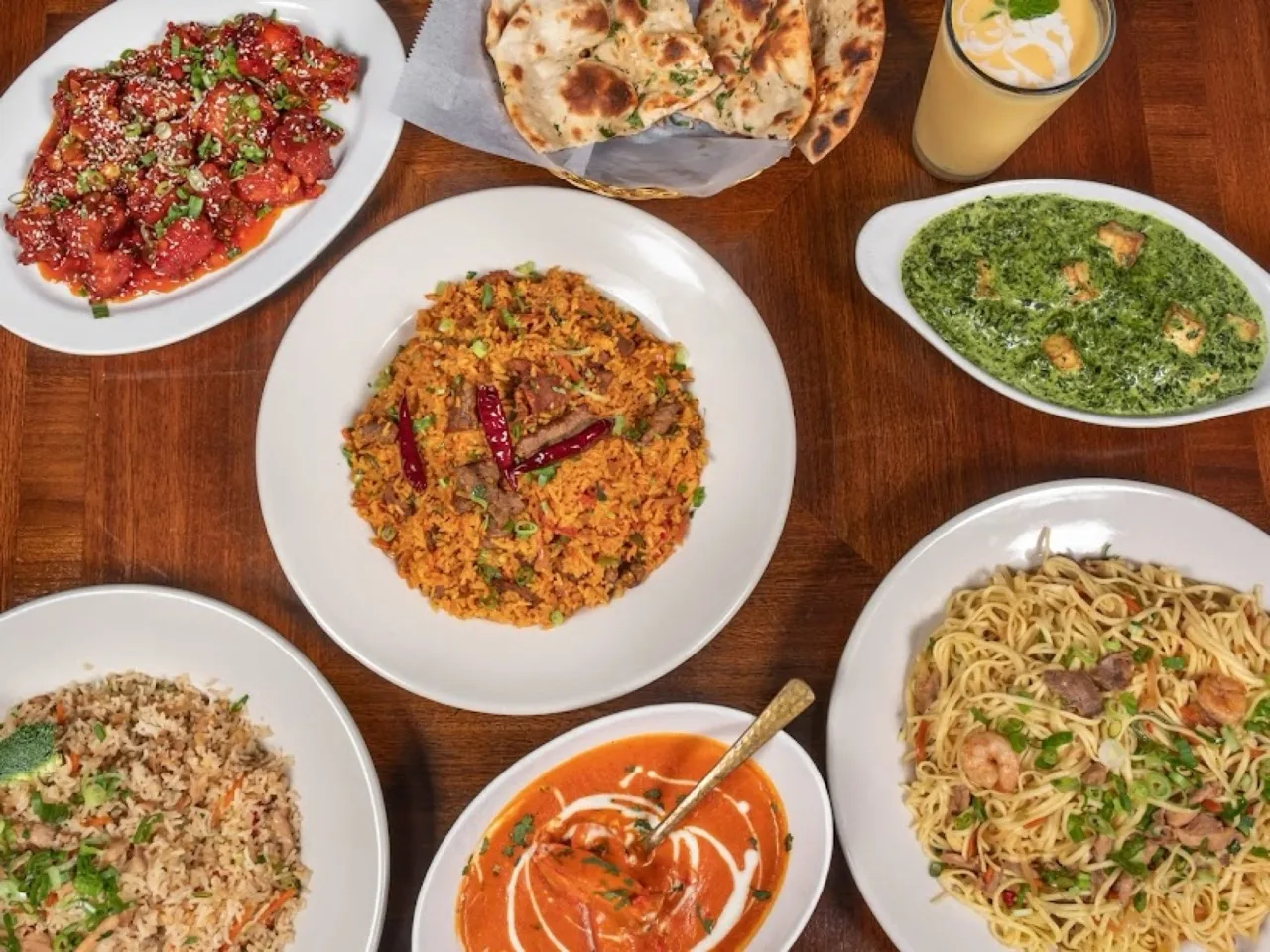 A spread of Chinese and Indian dishes laid out across a table